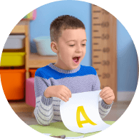 young boy holding up paper with letter 'A'